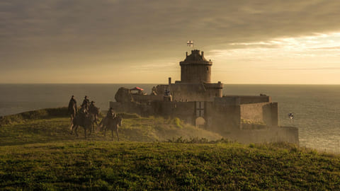 Cavaliers devant le fort La Latte au coucher du soleil